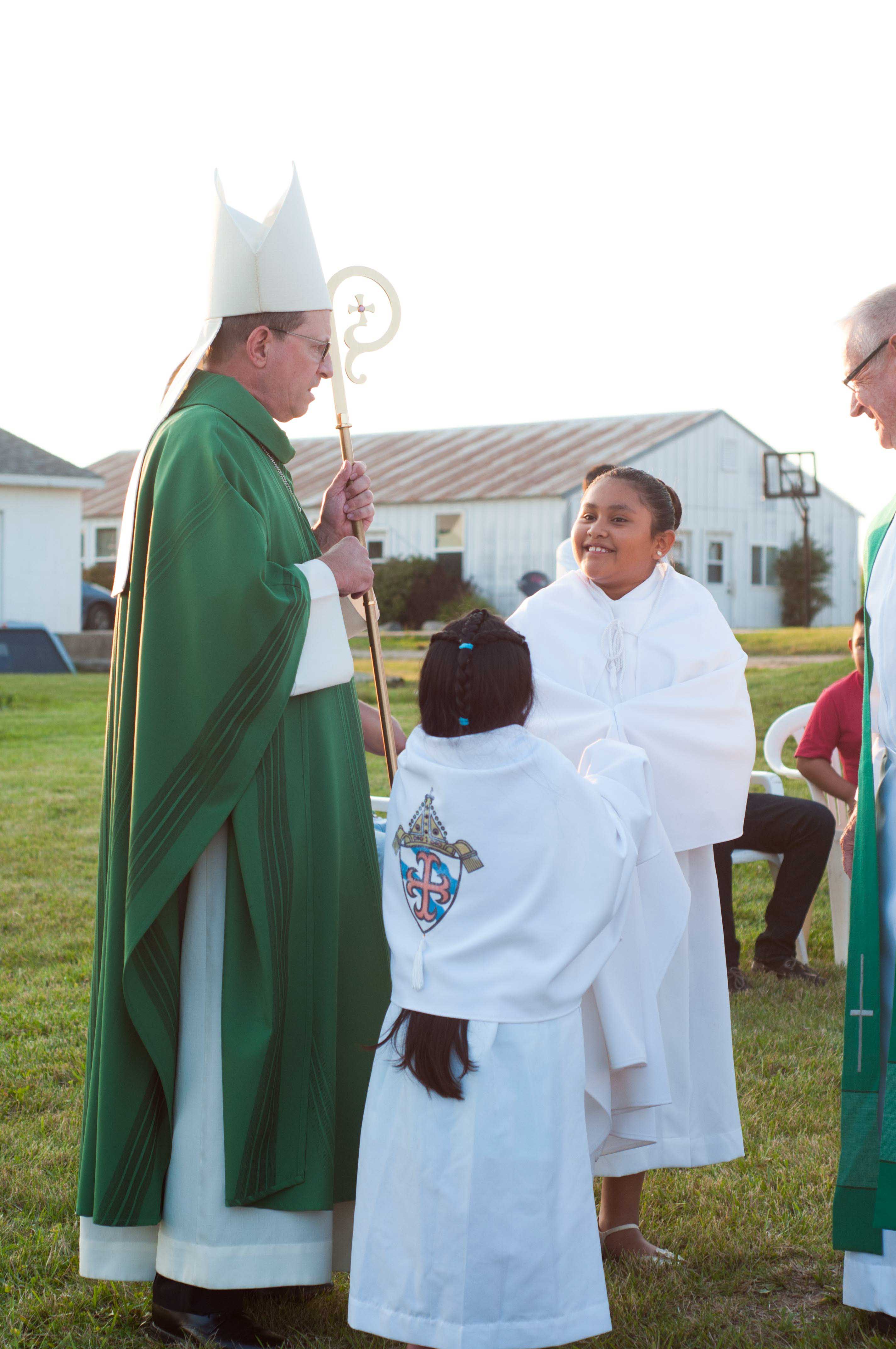 bishop walkowiak speaks with altar servers before a mass at a migrant camp in west michigan