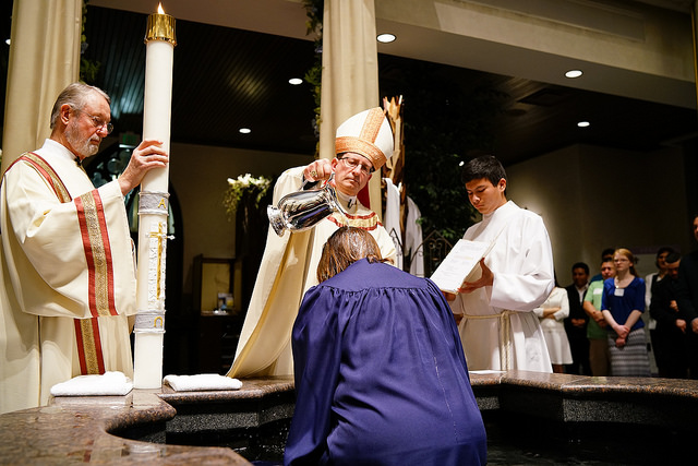 Bishop Walkowiak baptizes woman during the Easter Vigil at the Cathedral of Saint Andrew in Grand Rapids