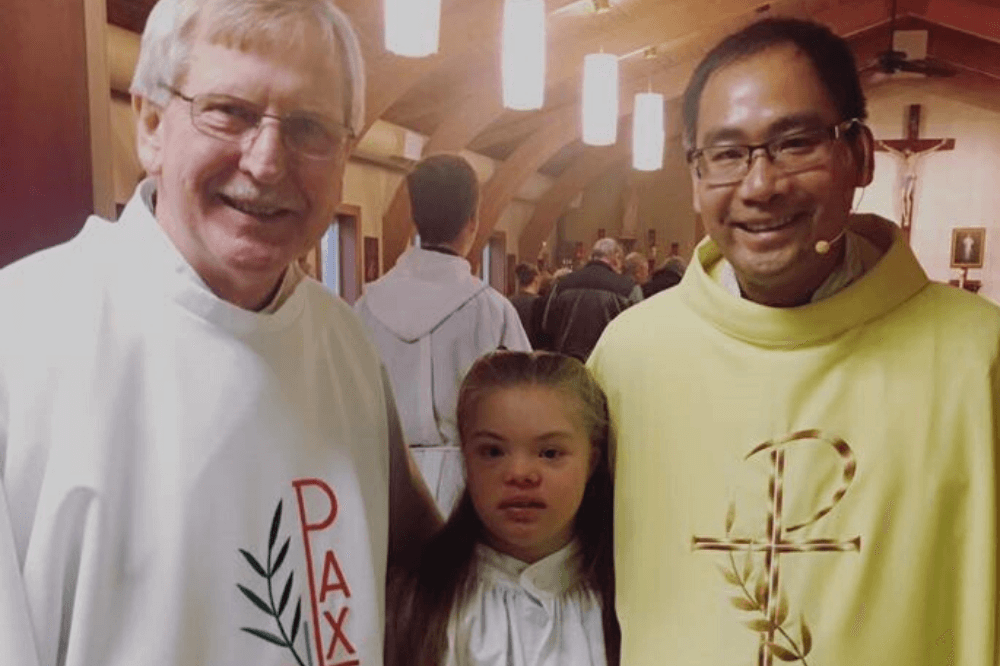 Sensory-friendly Mass photo with Father Lam, Deacon Falicki and young parish member with Down Syndrome
