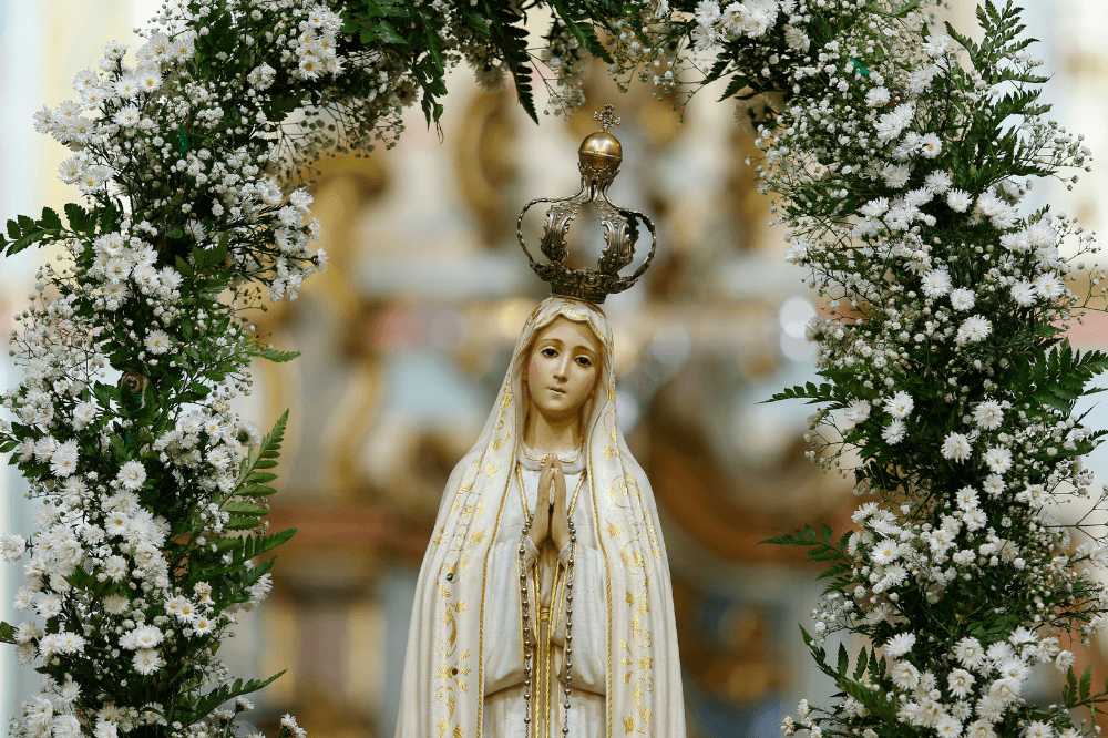 Image of statue of Our Lady of Fatima surrounded by arch of flowersholding rosary