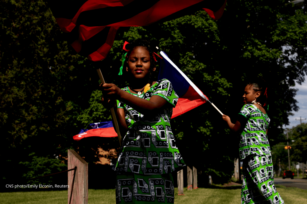 Two women wave flags during a Juneteenth celebration in Flint, Michigan