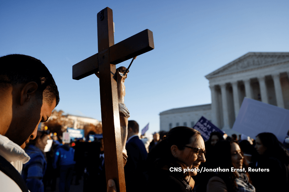 A pro-life activist holding a crucifix joins a protest outside the U.S. Supreme Court building