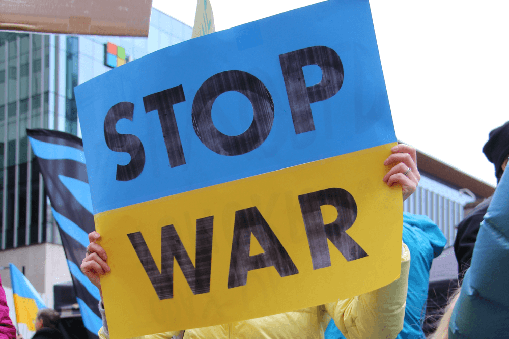Indivitual holding a "stop war" sign in colors of the Ukranian flag