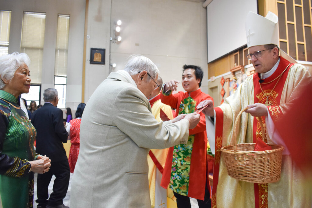 Bishop Walkowiak handing out red envelopes to celebrate the Lunar New Year.